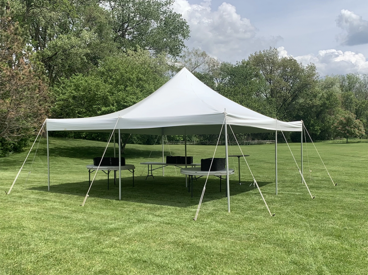 a 20x20 pole tent 48 guest package set up on grass grass with tree's in the background