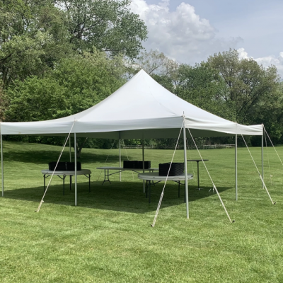 image of a 20x20 pole tent rental set up on grass with tables and chairs underneath