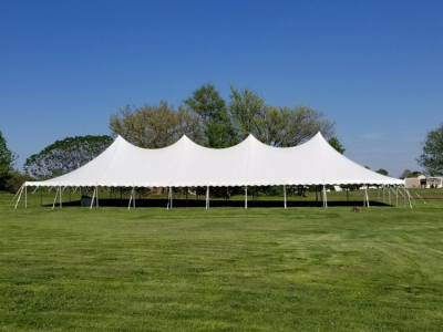 a 40x100 century pole tent with a white top set up at a farm for a festival